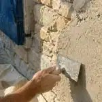Enduit chaux chanvre exterieur appliqué sur façade en pierre, fibres visibles