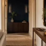 Déco hall d'entrée chic : mur bleu marine, console noyer, miroir et lumière chaude